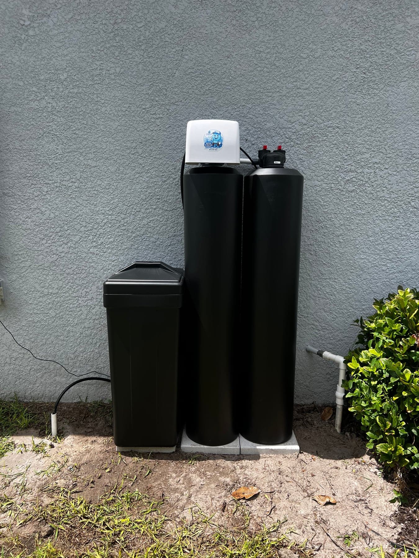 Outdoor black water softener and filtration tanks installed beside a Tampa Bay home